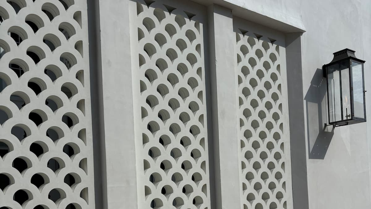 Three rectangular privacy wall panels with a repeating geometric arch pattern and a black metal wall lantern mounted on the right side.